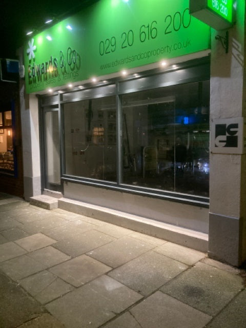 Image showing Aluminium and glass shopfront with green signage at night.