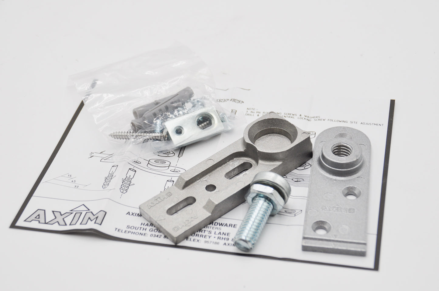An image showing the components of the Axim TC9500-17 Heavy Duty Bottom Pivot Set, which include aluminium pivot points and mounting hardware with fixings in clear packaging. On top of instructions with the word Axim printed on it. On a white background.