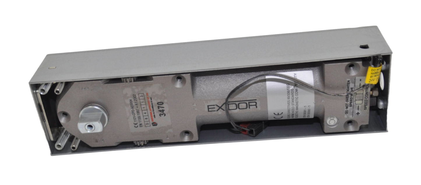 Exidor 3470 EMAG Floor Spring, an electromagnetic hold-open floor closer for heavy-duty doors, showing the mechanism within a metal housing box. On a white background.
