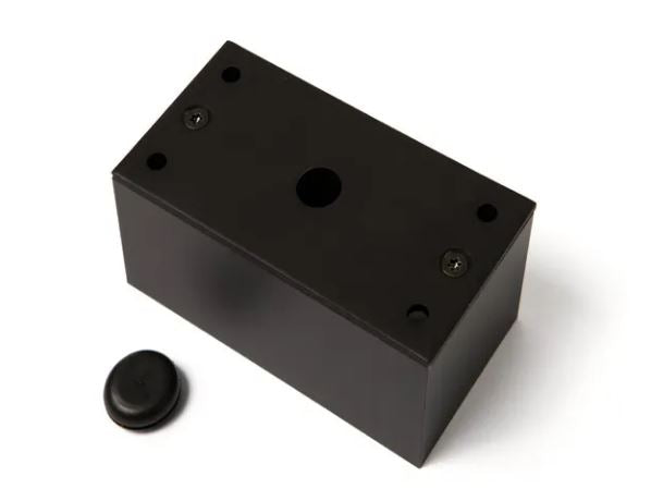 A mounting box consisting of a Black rectangular block with a smaller black round component on a white background