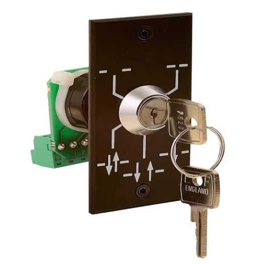 Assa Abloy key switch which consists of a black plate with white lines and arrows with key hole and 2 keys, on a white background.