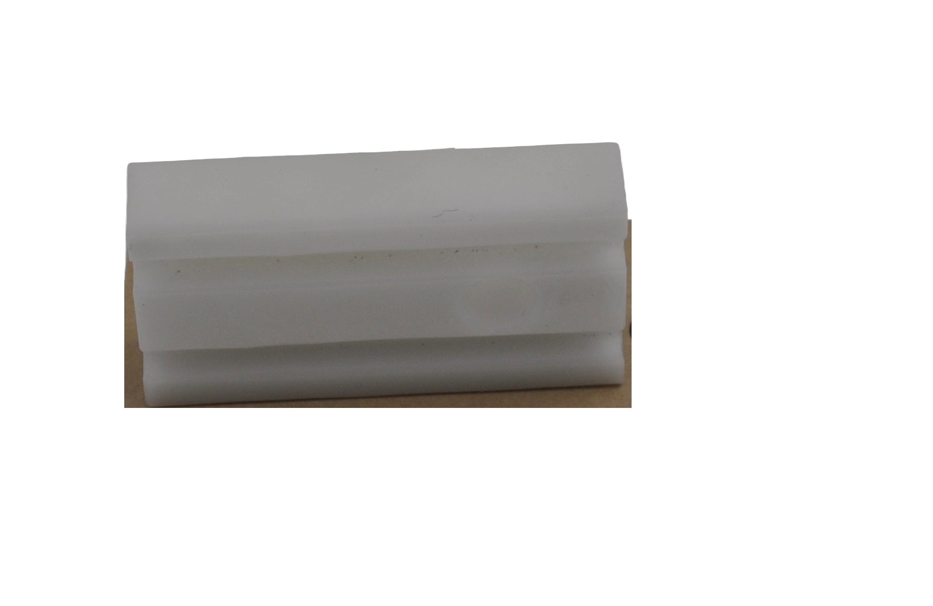 A view of a Besam breakout shoe which consists of a rectangular piece of plastic.  On a white background.